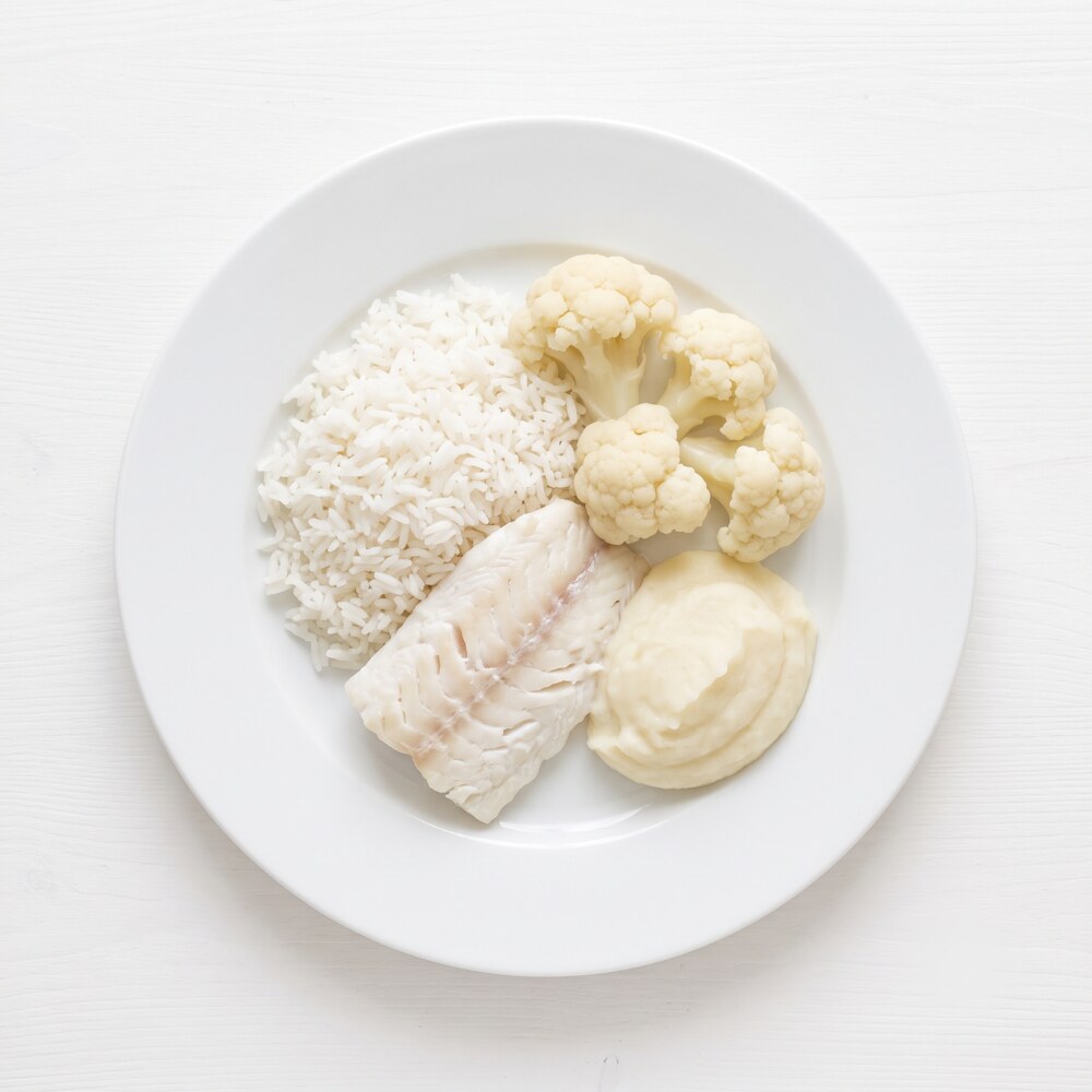 Jasny obiad na białym talerzu: ryż, ryba, kalafior, purée